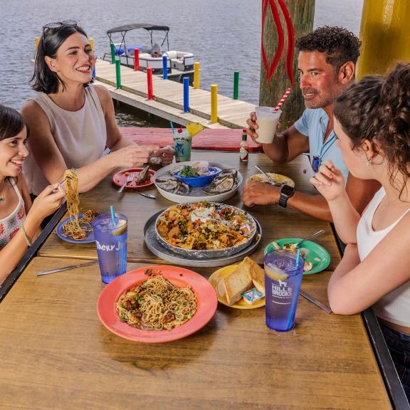 Family dining at a table full of seafood at Tacky Jacks waterfront restaurant in Orange Beach